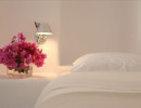 all white bedroom decor with fuschia flowers by bedside
